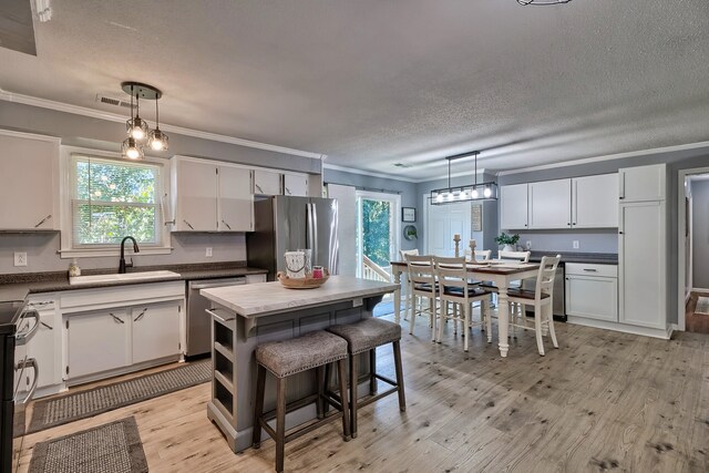 kitchen featuring a wealth of natural light, appliances with stainless steel finishes, sink, and white cabinets