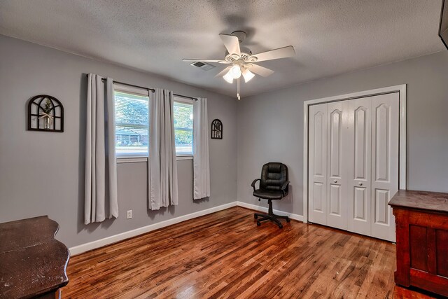 miscellaneous room featuring wood-type flooring, ceiling fan, and a textured ceiling