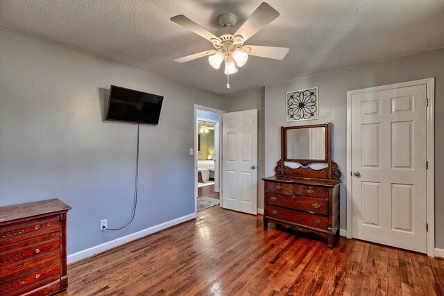 bedroom with dark wood-type flooring, a textured ceiling, and ceiling fan