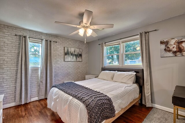 bedroom featuring a textured ceiling, dark hardwood / wood-style flooring, brick wall, and ceiling fan