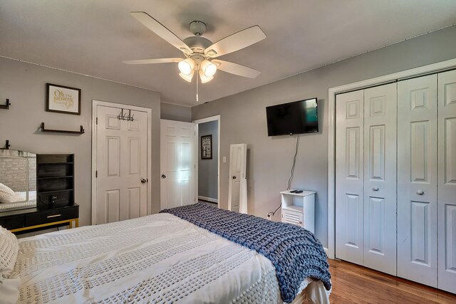 bedroom featuring ceiling fan, multiple closets, and light hardwood / wood-style flooring