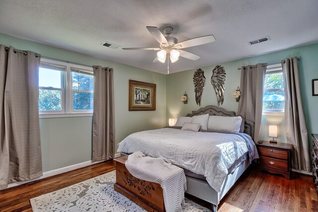 bedroom with a textured ceiling, hardwood / wood-style flooring, and ceiling fan