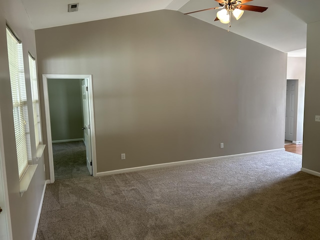 carpeted spare room featuring ceiling fan, vaulted ceiling, healthy amount of natural light, and baseboards
