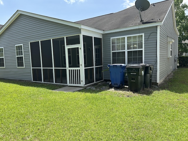 back of property featuring a sunroom, a lawn, and a shingled roof
