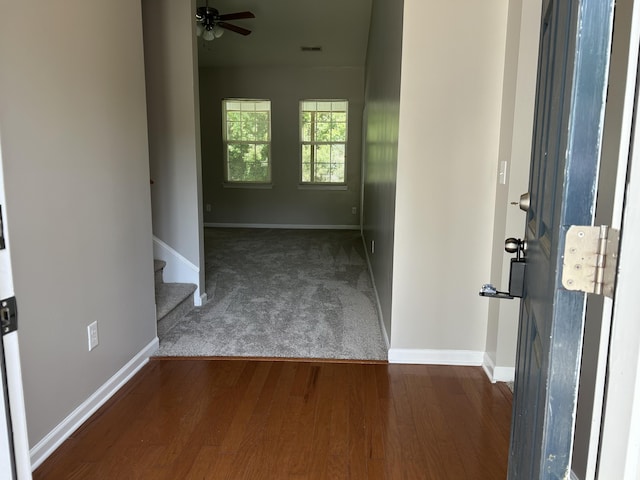 carpeted foyer with baseboards, wood finished floors, and stairway