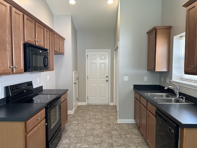 kitchen featuring black appliances, a sink, dark countertops, baseboards, and brown cabinetry