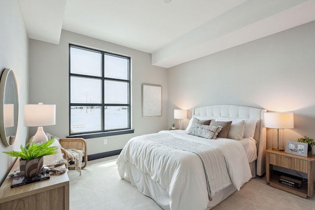 bedroom featuring light carpet, multiple windows, and baseboards