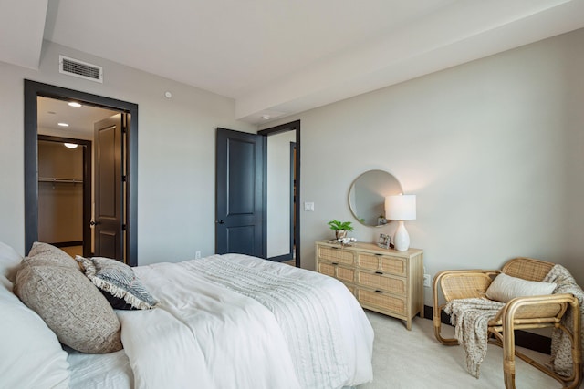bedroom with light carpet, a walk in closet, and recessed lighting