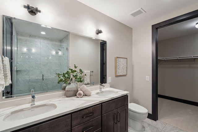 full bath with a stall shower, toilet, marble look tile flooring, double vanity, and a walk in closet