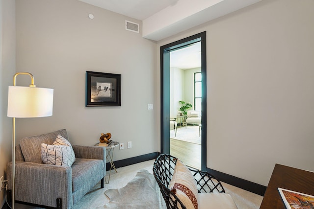 living area featuring light colored carpet and baseboards