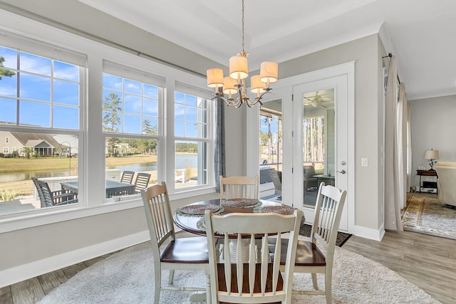 dining area with wood-type flooring, a water view, and an inviting chandelier