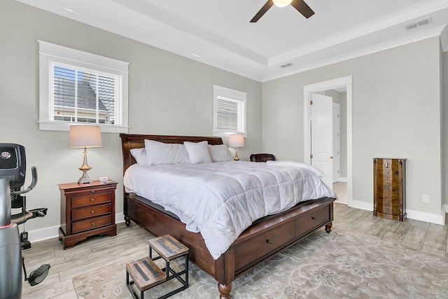 bedroom featuring ceiling fan, a raised ceiling, and light wood-type flooring