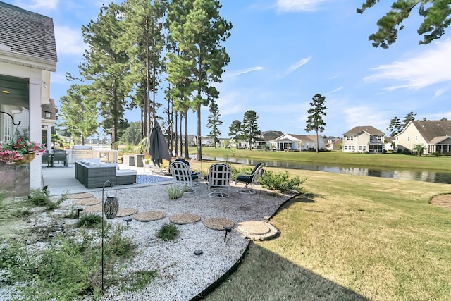 view of yard with an outdoor living space, a patio, and a water view