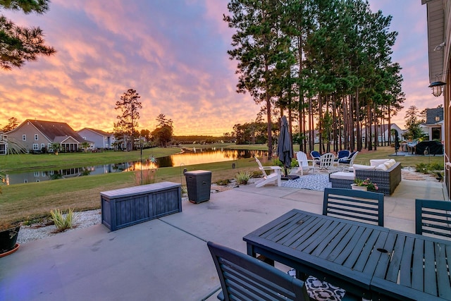 patio terrace at dusk with a yard, outdoor lounge area, and a water view