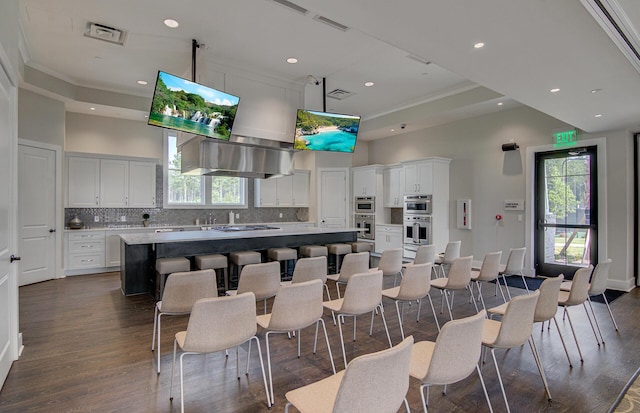 kitchen featuring a towering ceiling, a center island, white cabinets, and a breakfast bar