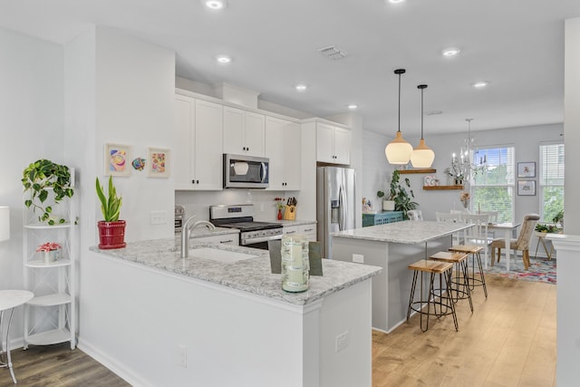 136 Rowans Creek Dr, Charleston, SC 29492 - kitchen with stainless steel appliances, a kitchen island, light wood-style flooring, a breakfast bar, and white cabinetry