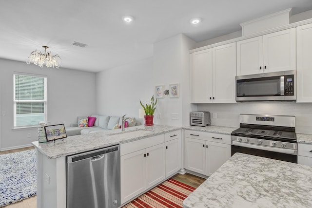 136 Rowans Creek Dr, Charleston, SC 29492 - kitchen featuring stainless steel appliances, a peninsula, light wood-style flooring, a chandelier, and white cabinets