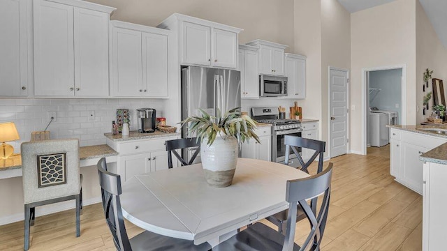 544 Verdi Dr, Summerville, SC 29486 - kitchen with appliances with stainless steel finishes, separate washer and dryer, decorative backsplash, light wood-style flooring, and white cabinetry