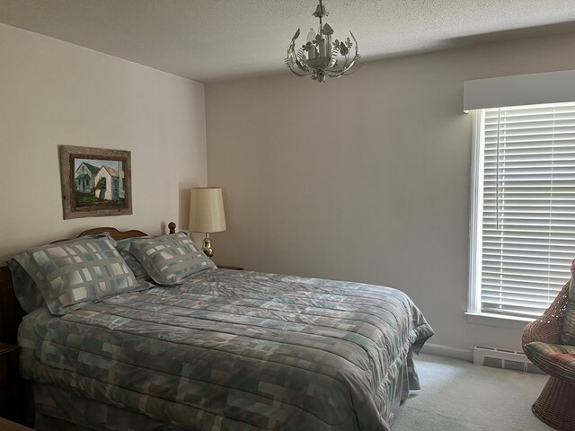 carpeted bedroom with a chandelier and a textured ceiling