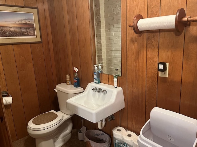 bathroom featuring wooden walls, toilet, and sink