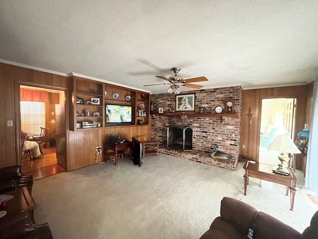 carpeted living room featuring a brick fireplace, ceiling fan, ornamental molding, and a textured ceiling