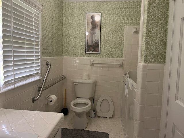 bathroom with washer / dryer, tile walls, tile patterned floors, independent shower and bath, and toilet