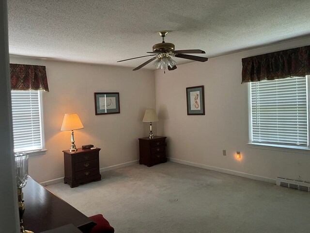 unfurnished room with ceiling fan, a textured ceiling, and light carpet