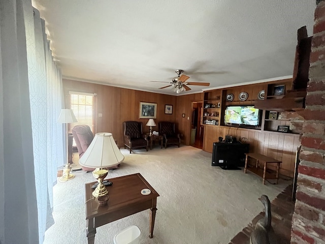 carpeted living room with ceiling fan, a textured ceiling, wood walls, and ornamental molding