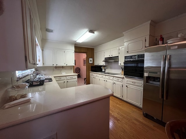 kitchen with hardwood / wood-style floors, kitchen peninsula, ornamental molding, white cabinets, and black appliances