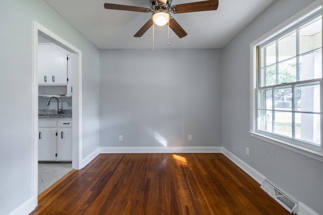 unfurnished room with dark hardwood / wood-style flooring, ceiling fan, a healthy amount of sunlight, and sink