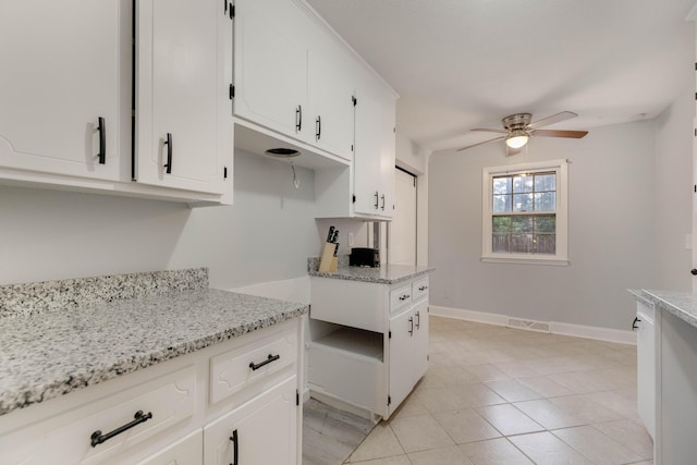 kitchen with white cabinetry, ceiling fan, light tile patterned floors, and light stone countertops