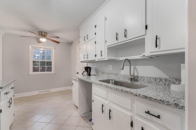 kitchen featuring white cabinets, sink, ceiling fan, light stone countertops, and light tile patterned flooring