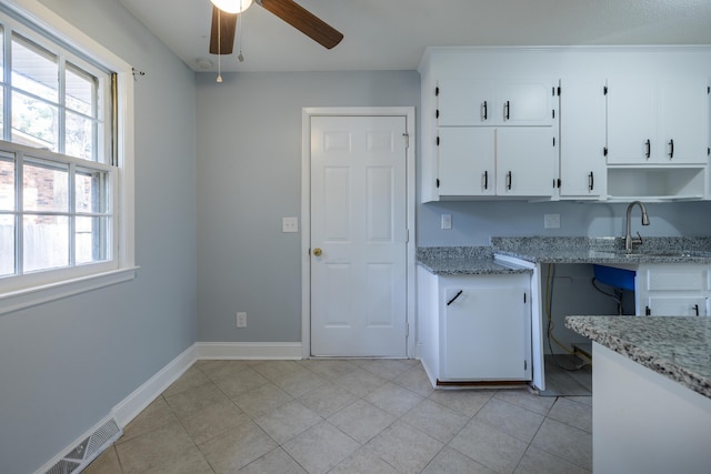 kitchen with light stone countertops, white cabinets, and sink