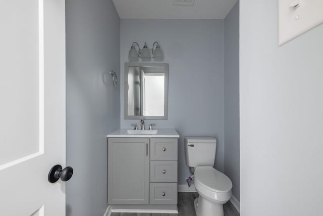 bathroom with hardwood / wood-style flooring, vanity, and toilet