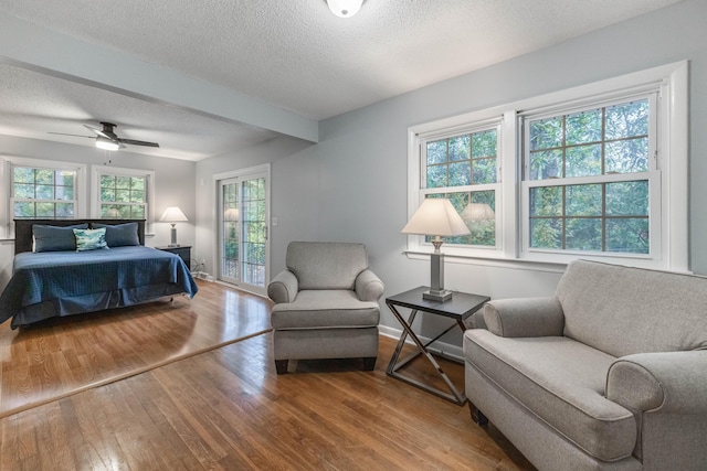 bedroom featuring ceiling fan, access to exterior, wood-type flooring, and a textured ceiling