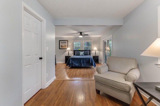 bedroom with ceiling fan, wood-type flooring, and a textured ceiling