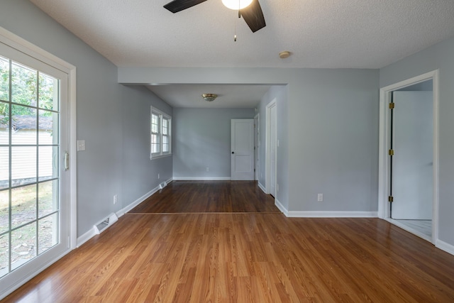 spare room featuring a healthy amount of sunlight, wood-type flooring, and a textured ceiling