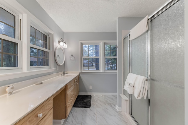 bathroom featuring vanity, a shower with shower door, and a textured ceiling