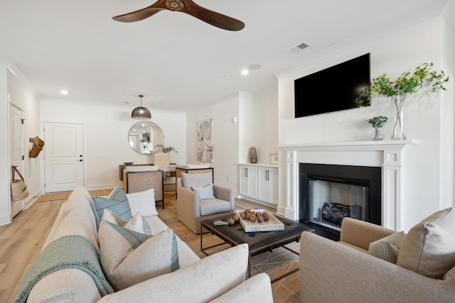 living room featuring ceiling fan, ornamental molding, and light hardwood / wood-style floors