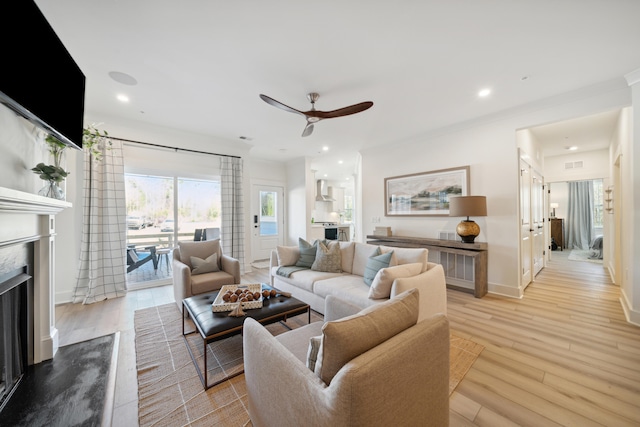 living room with light hardwood / wood-style floors, ceiling fan, and crown molding