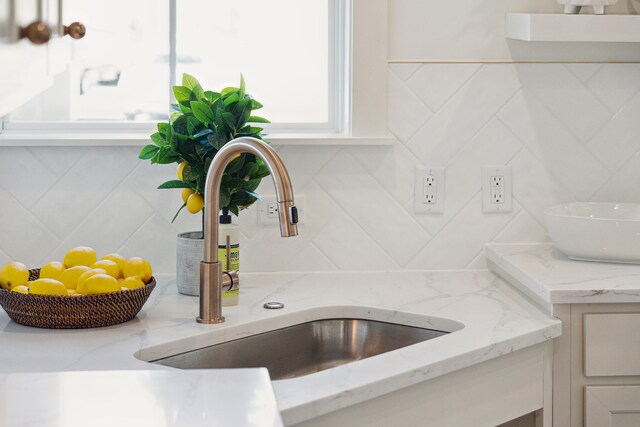 room details with light stone counters, backsplash, and sink