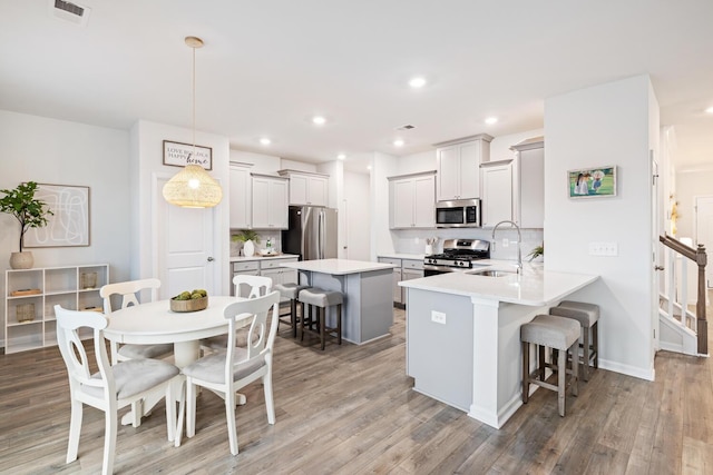 kitchen with a breakfast bar, decorative light fixtures, sink, kitchen peninsula, and stainless steel appliances