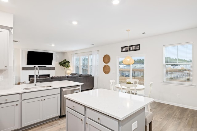 kitchen with stainless steel dishwasher, sink, hanging light fixtures, and gray cabinetry