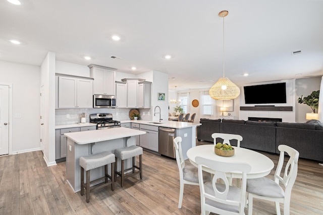 kitchen featuring sink, hanging light fixtures, appliances with stainless steel finishes, gray cabinets, and kitchen peninsula