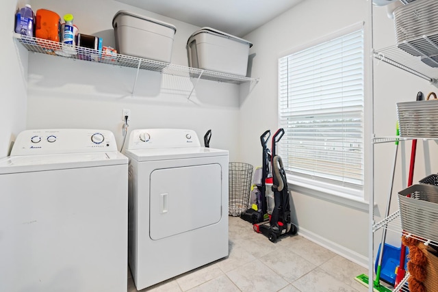 washroom with washing machine and dryer, a healthy amount of sunlight, and light tile patterned flooring