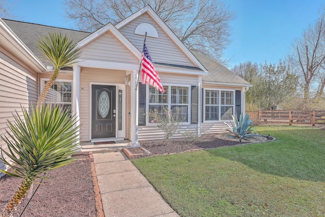 view of front of property featuring a shingled roof, fence, and a front lawn