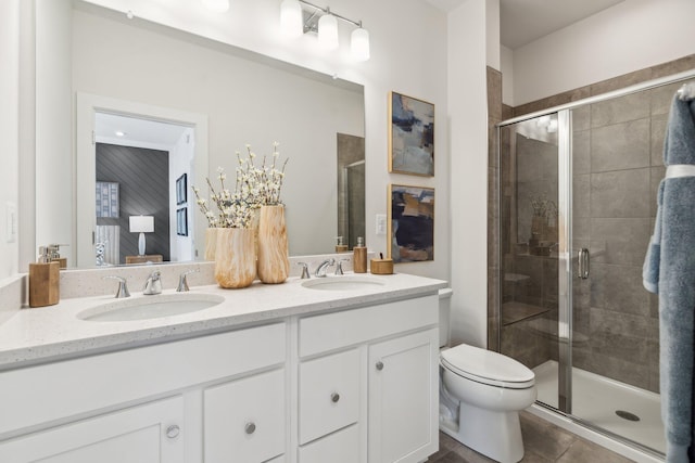 full bath featuring a stall shower, double vanity, toilet, and tile patterned floors