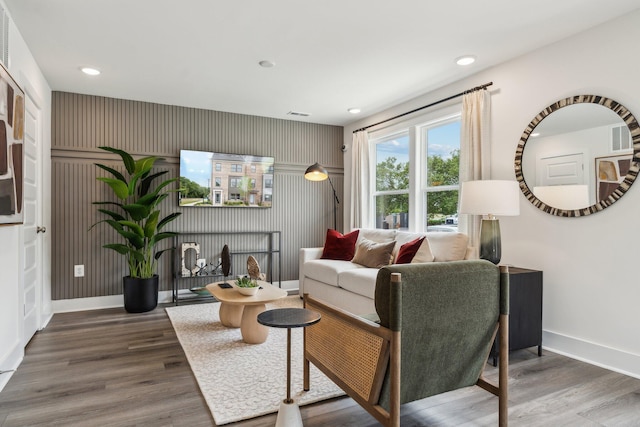 living room featuring baseboards, wood finished floors, recessed lighting, and an accent wall