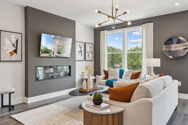living room with a chandelier, baseboards, and dark wood-style floors