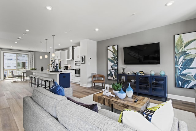 living room with light wood-type flooring, baseboards, and recessed lighting